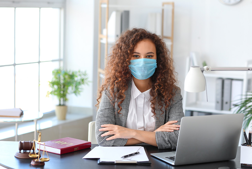 Lawyer woman sitting at her desk and wearing a mask