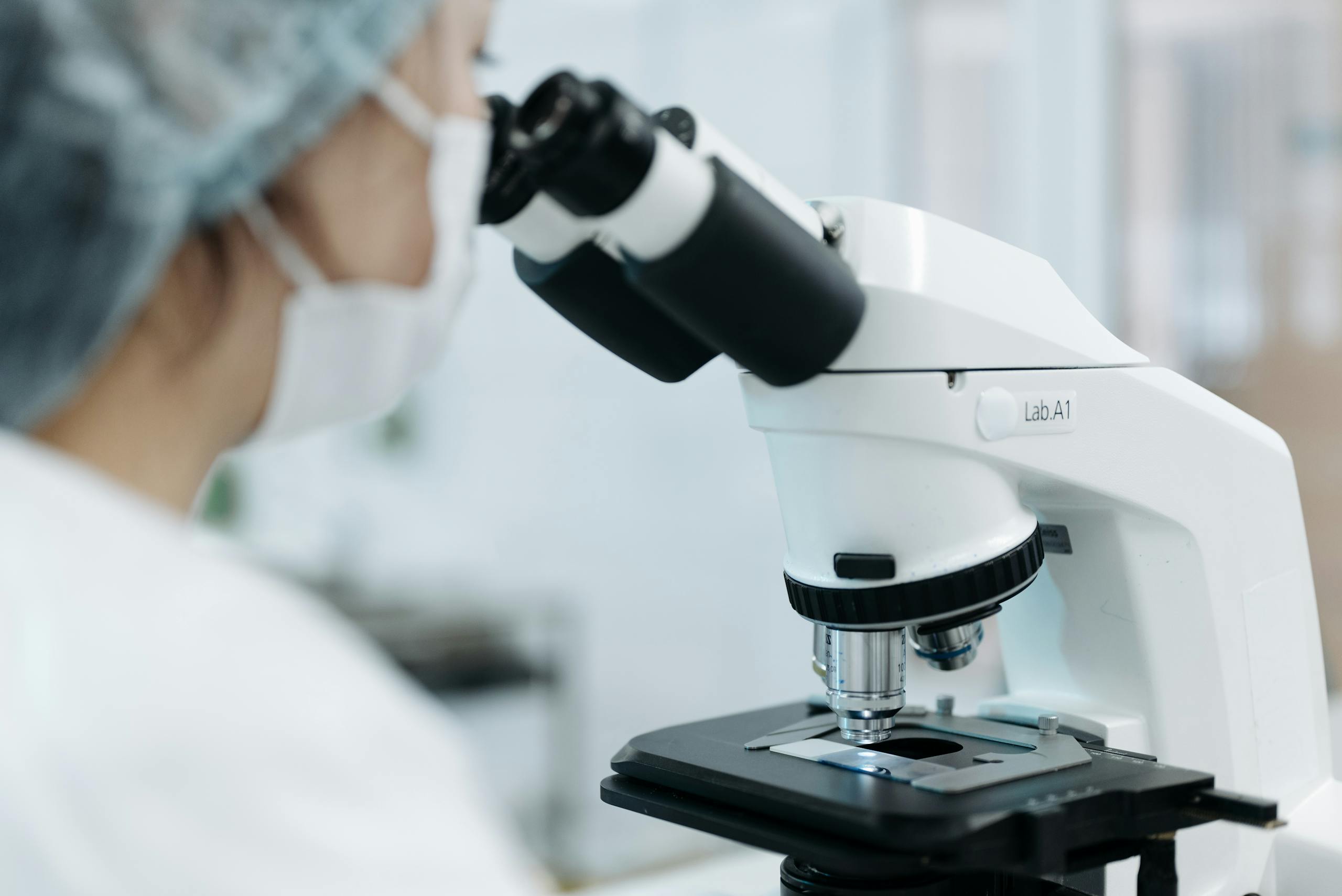 Scientist using a microscope in a laboratory environment. Focus on research and analysis.